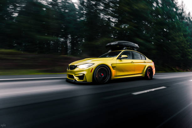 Seattle, WA, USA May 24, 2022 Yellow BMW M4 F82 with roof rack parked in a parking lot with rock on the ground